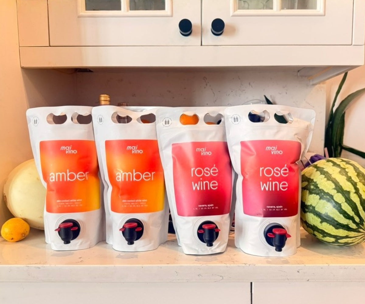 Two amber and two rosé Mai Vino pouches on a kitchen counter with melons